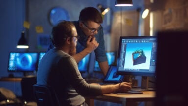 Two designers working on 3D model at computer