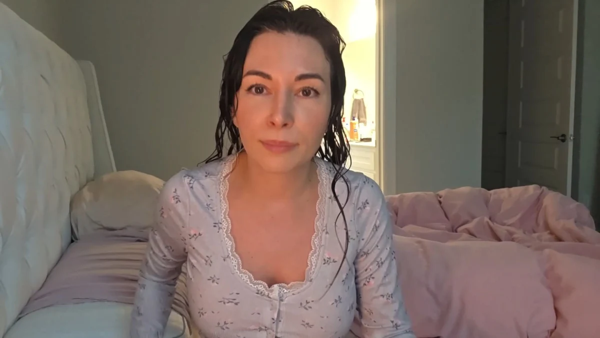 Woman with wet hair sitting on bed in bedroom