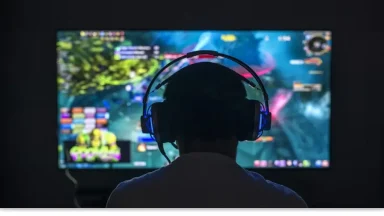 Gamer with headset playing video game on screen.