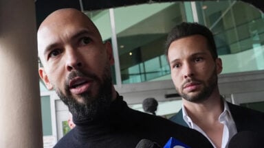Two men speaking to reporters outside building
