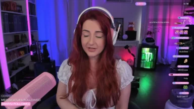 Red-haired streamer wearing headphones in colorful gaming room