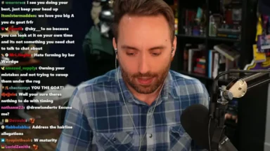 Streamer in plaid shirt reads live chat beside microphone