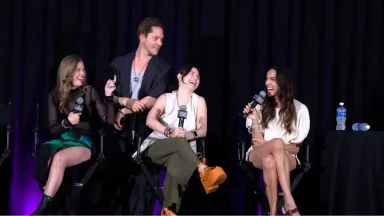 Four people laughing on stage with microphones.