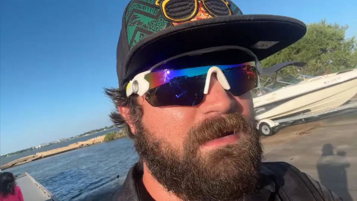 Bearded man wearing mirrored sunglasses beside a boat ramp