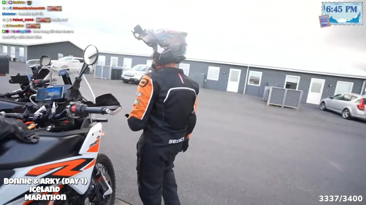 Motorcyclist prepares beside adventure bike in Iceland lodging parking lot.