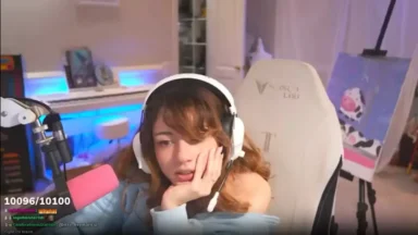 Streamer wearing headphones sits beside pink microphone