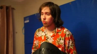 Person in floral shirt holding boxing gloves indoors