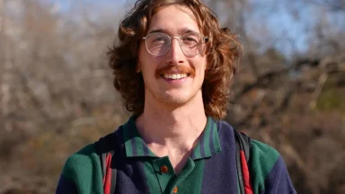 Smiling man with glasses outdoors wearing backpack