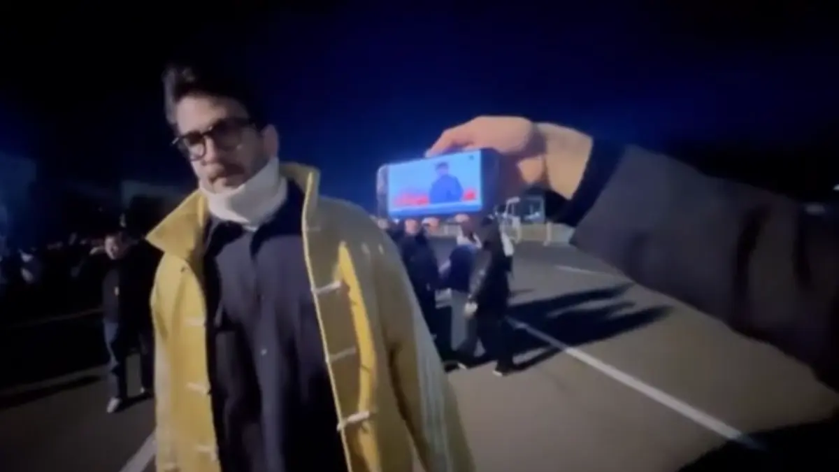 Person in yellow coat filmed on smartphone at night