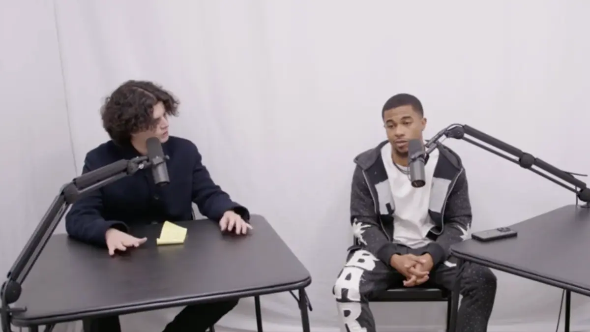 Two men speaking into microphones at podcast table