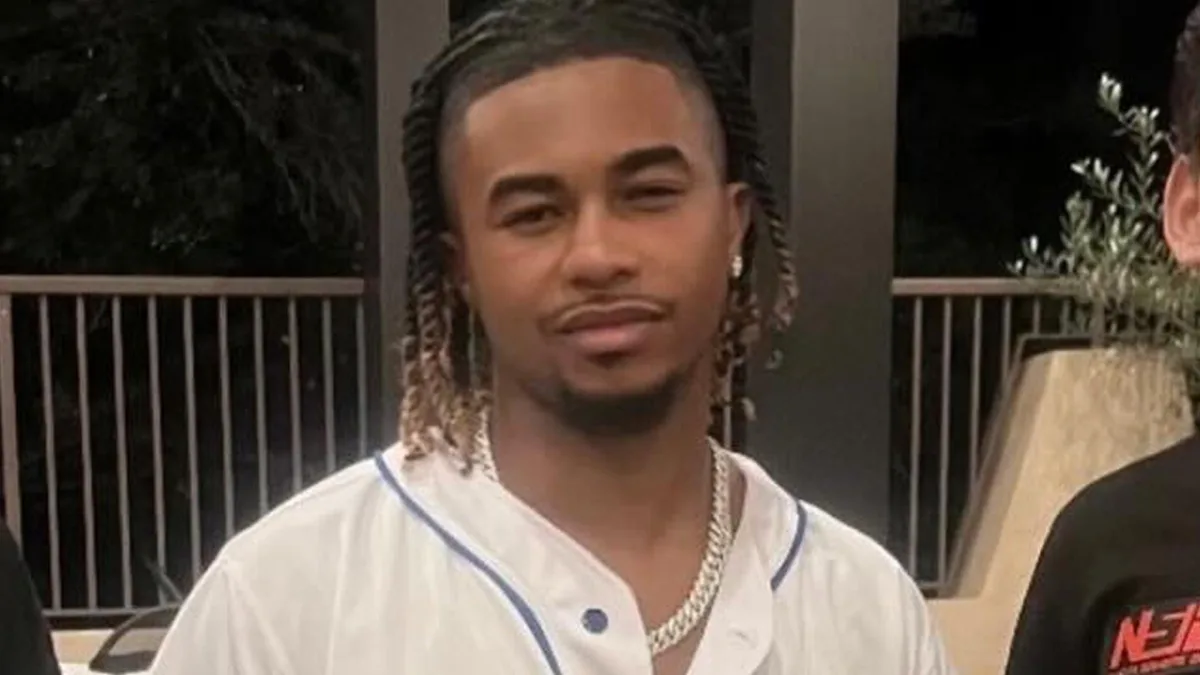 Young man with braids wearing baseball-style jersey