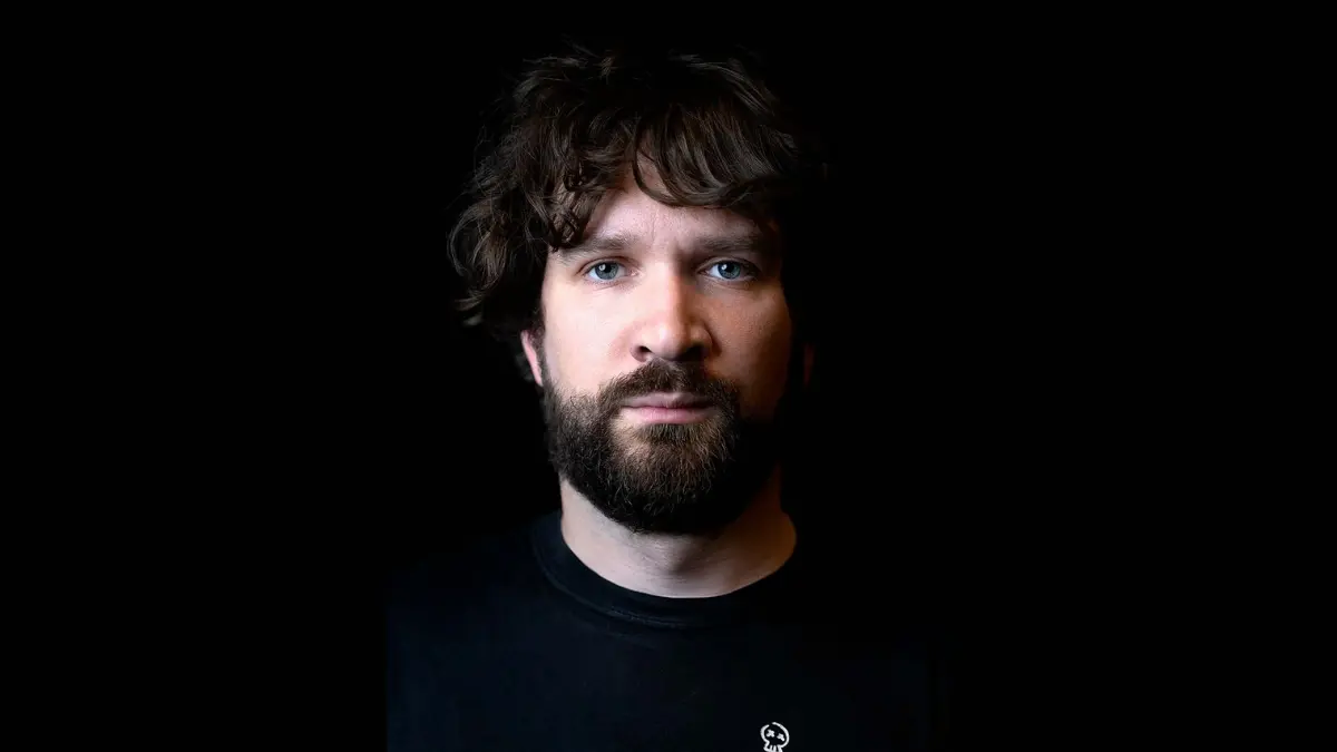 Person with beard in front of black background.
