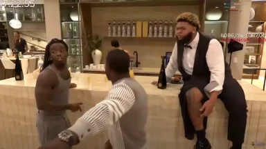 Three men talking near a bar counter indoors.