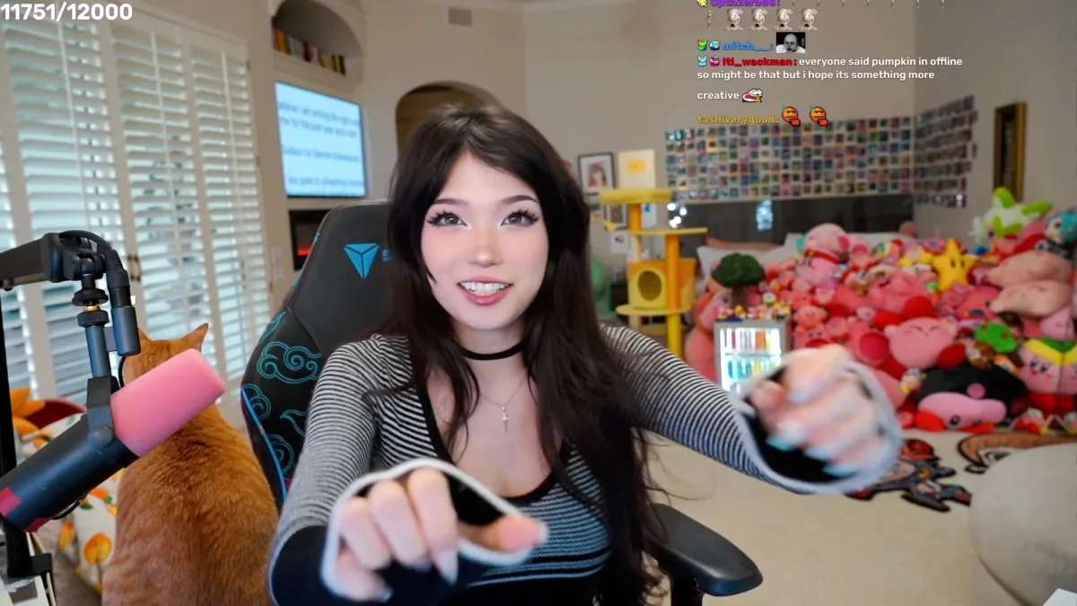 Streamer smiles while holding a cable beside her cat