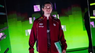 Man in red team jacket on neon-lit stage