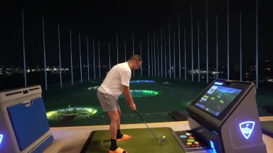 Man golfing at night with digital screen display.