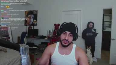 Streamer speaking in cluttered room with poster and cutout