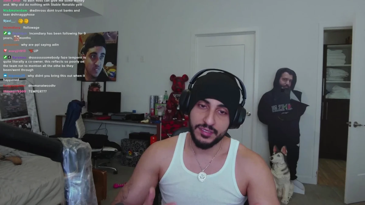 Streamer speaking in cluttered room with poster and cutout