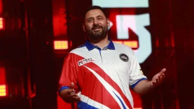Man speaking on stage in red jersey