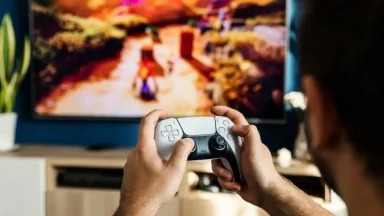 Person playing video game on TV with controller