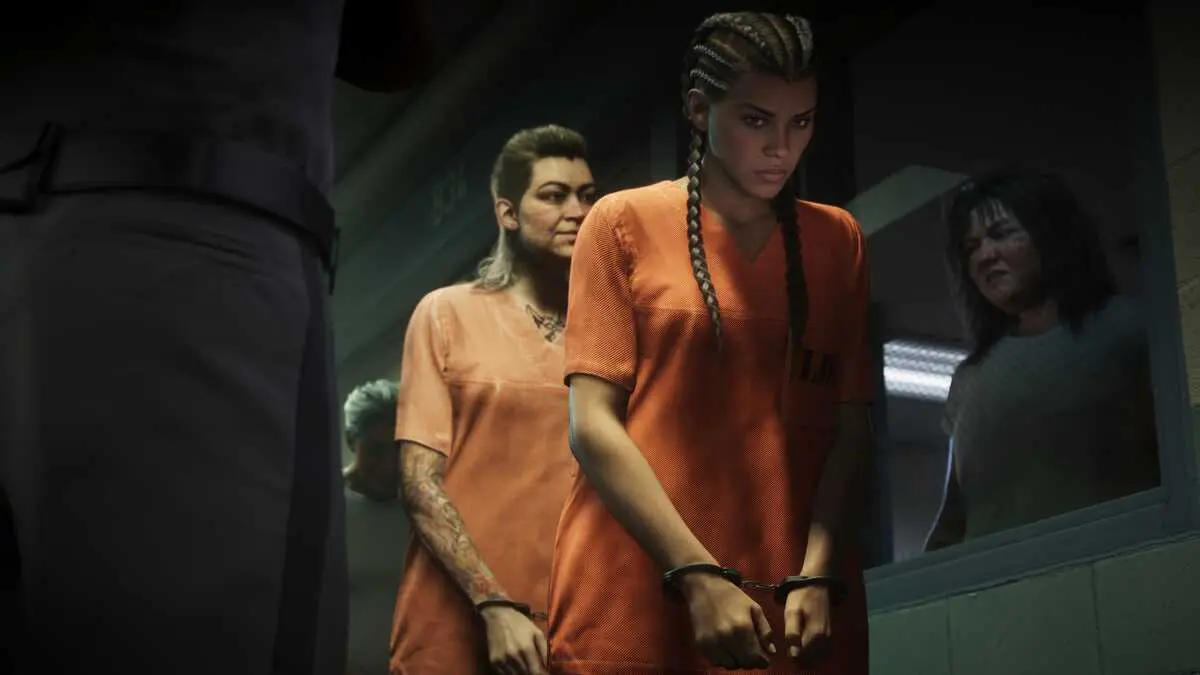 Handcuffed women in orange jail uniforms stand in line