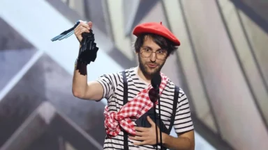 Man in beret holding award on stage
