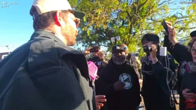 Man speaking to crowd filming outdoors