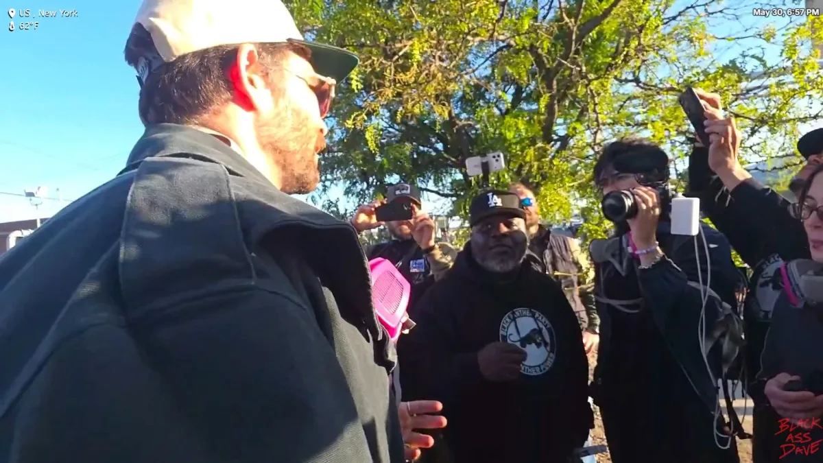 Man speaking to crowd filming outdoors