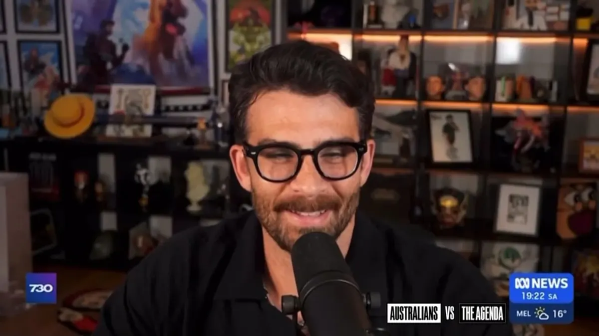 Person speaking into a microphone, shelves in background.