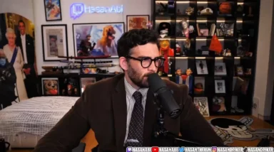 HasanAbi speaking into microphone in memorabilia-filled studio
