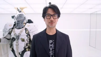 Hideo Kojima stands beside futuristic white armored robot