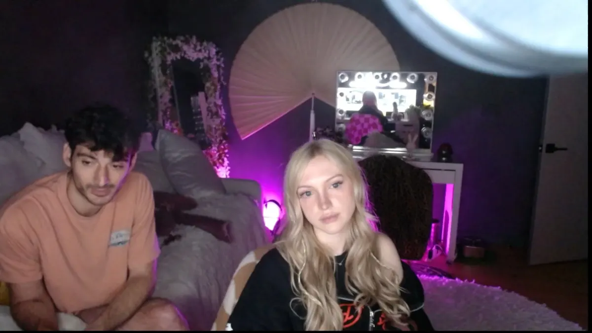 Two people sitting in purple-lit bedroom setup