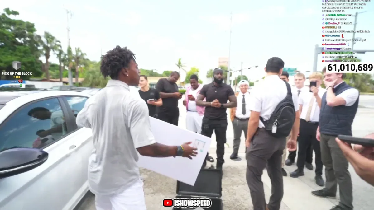 Man holds box beside white car before crowd