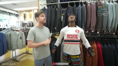 Two men inside clothing store with suits displayed.