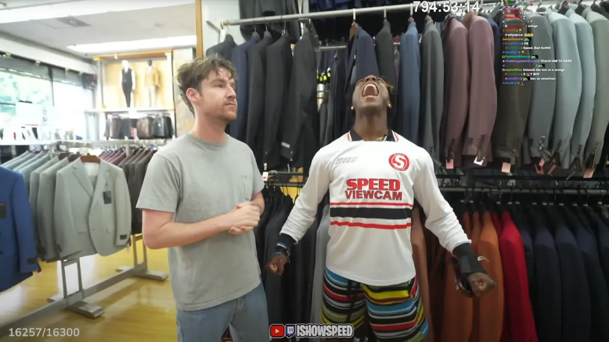 Two men inside clothing store with suits displayed.