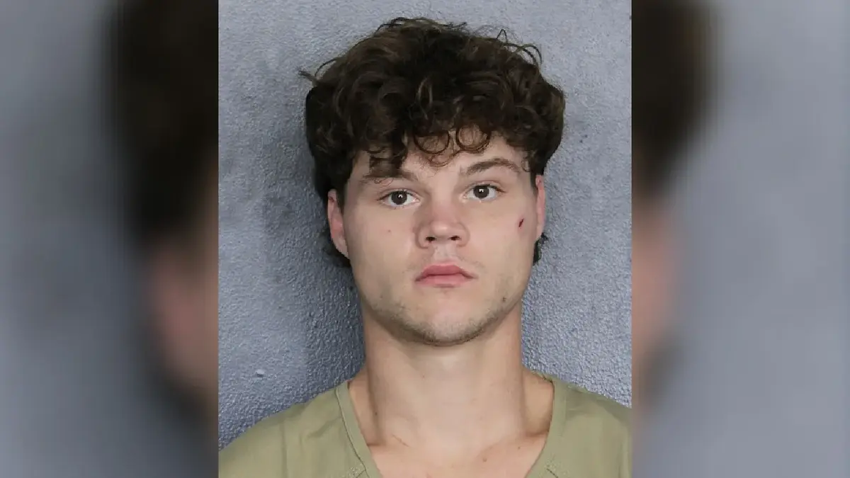 Mugshot-style portrait of young man with curly dark hair