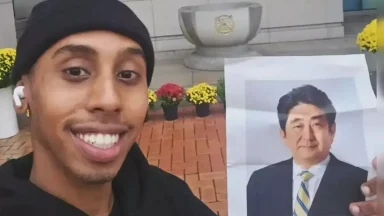 Person smiling, holding a portrait outdoors.