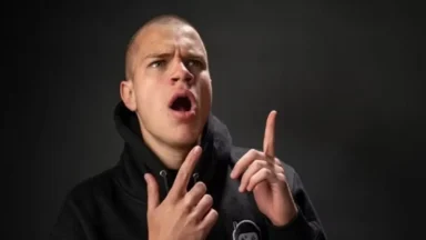 Surprised young man pointing upward in dark studio