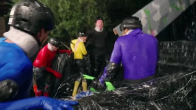 People in colorful suits compete in outdoor challenge.