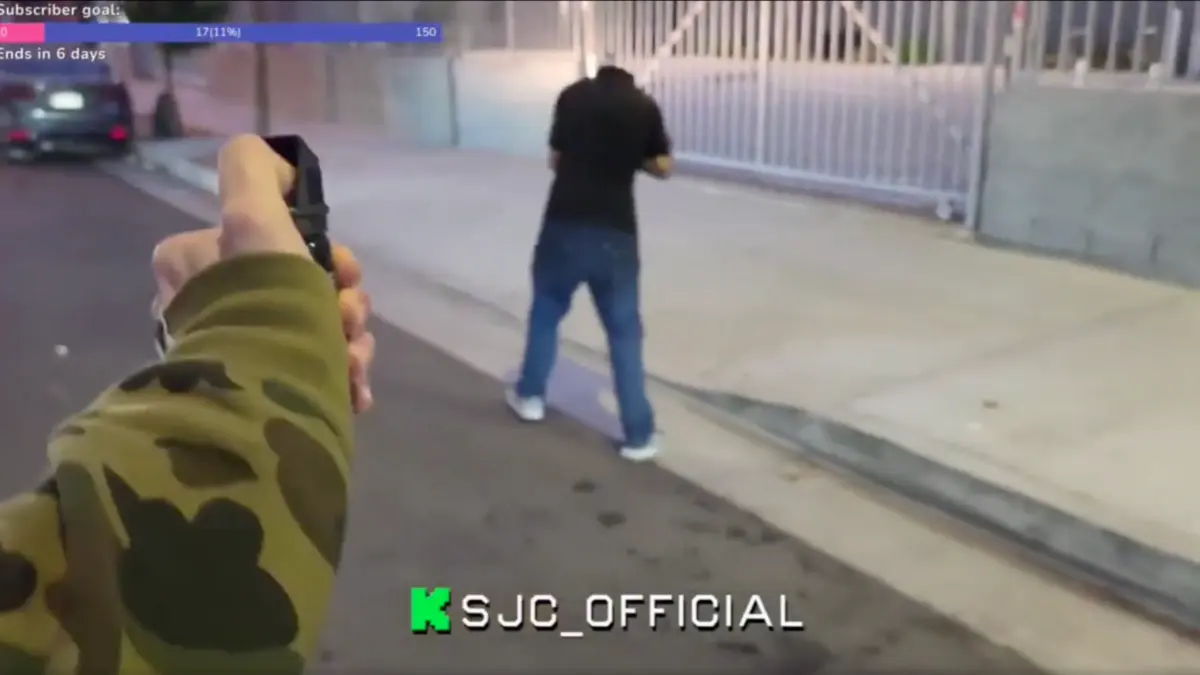 Person pointing gun at man on street