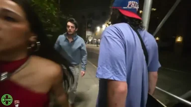 Three people stand on a city sidewalk at night.