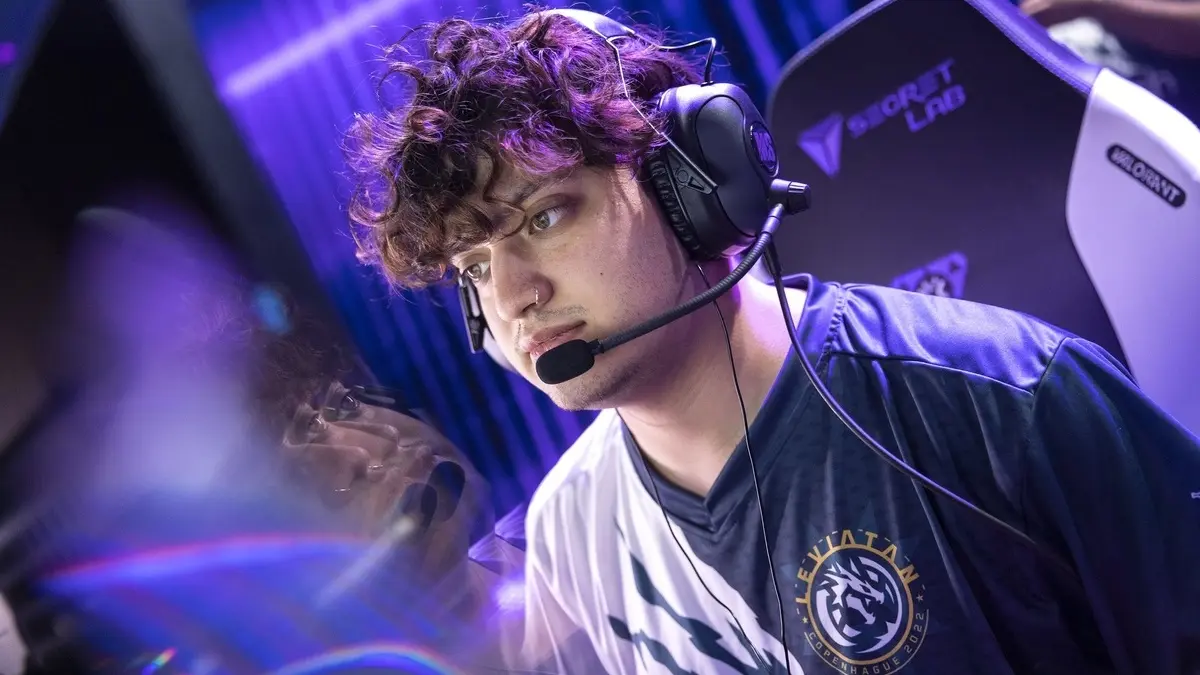 Focused esports player wearing headset under purple stage lights