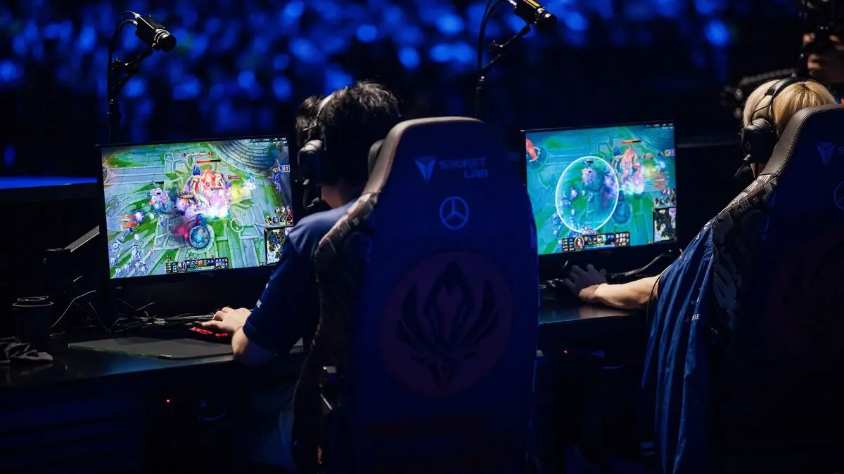 Esports players competing on computers under blue arena lighting