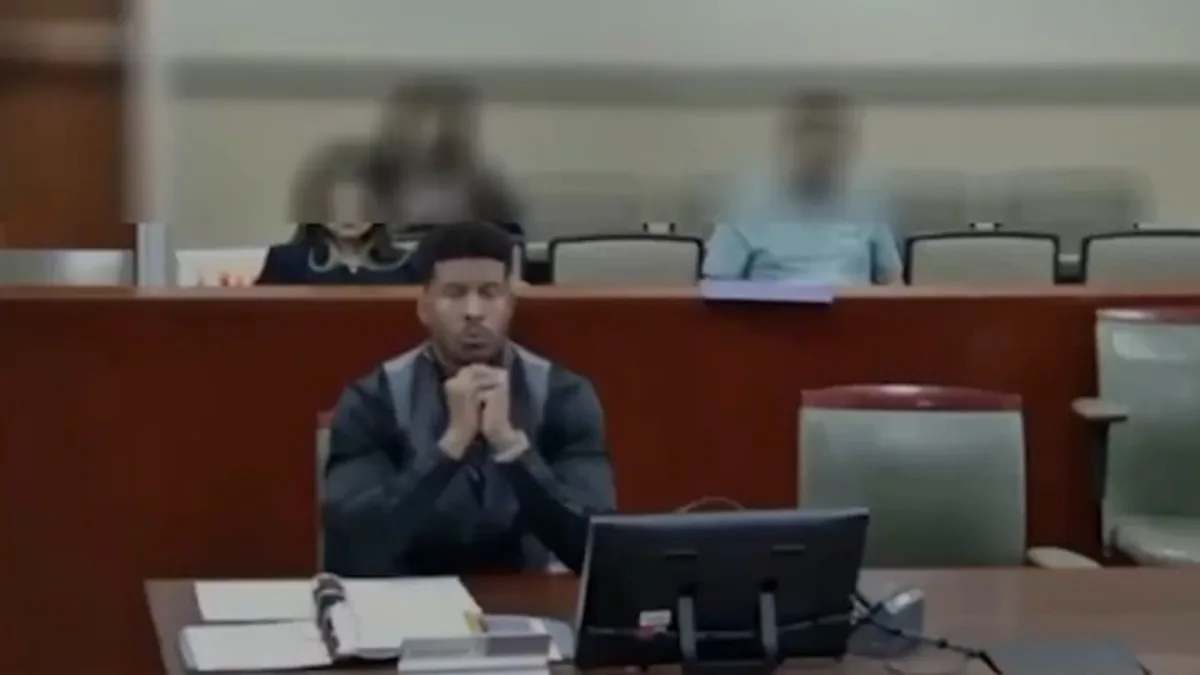 Man seated at courtroom desk with computer monitor