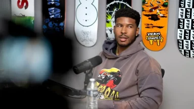 Person speaking into microphone, skateboard art background.