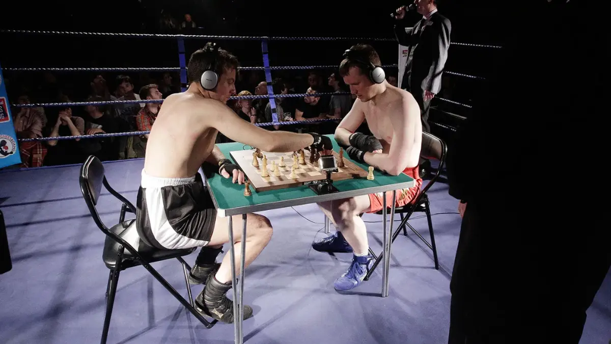 Two boxers playing chess in a boxing ring.