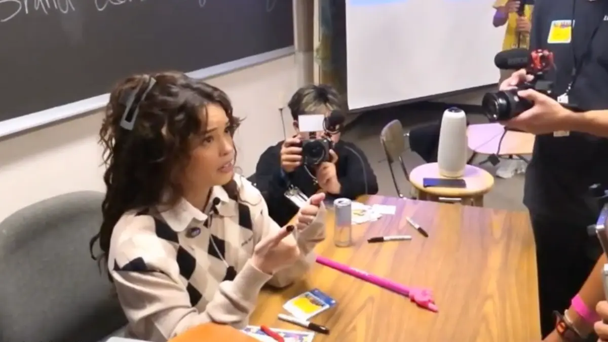 Woman signing autographs while photographers take pictures