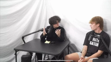 Two people talking into microphones during podcast recording.