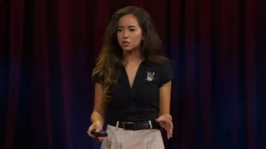 Woman giving presentation on stage with red curtains