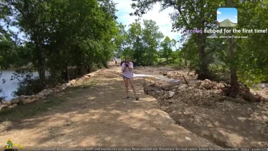Person walking on washed-out dirt path after flood.